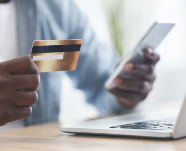 Black man using card and smartphone for paying bills online