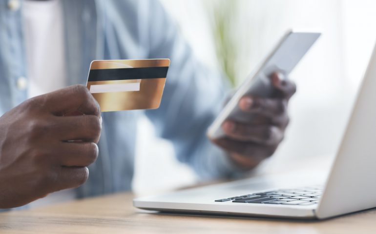 Black man using card and smartphone for paying bills online